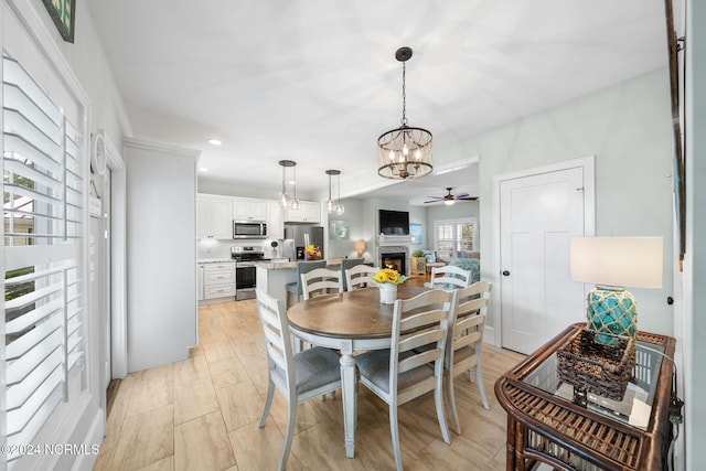 112 NE 28th St, Oak Island, NC 28465 - dining area featuring a chandelier, a fireplace, a ceiling fan, and recessed lighting