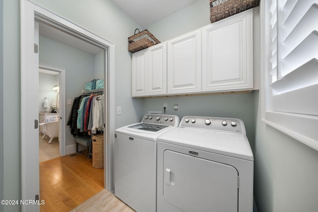 laundry area with washer and clothes dryer, cabinets, and light hardwood / wood-style flooring