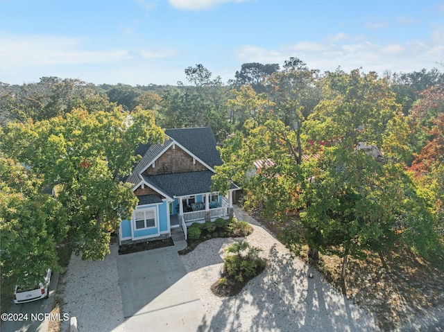 112 NE 28th St, Oak Island, NC 28465 - view of front facade with covered porch, a view of trees, a shingled roof, and concrete driveway