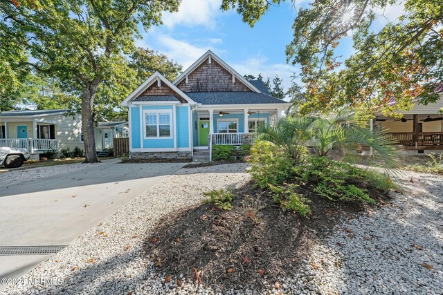 112 NE 28th St, Oak Island, NC 28465 - view of front facade with covered porch, a ceiling fan, concrete driveway, and stone siding