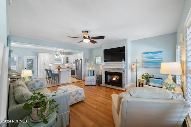 living room featuring ceiling fan, light hardwood / wood-style floors, and a high end fireplace