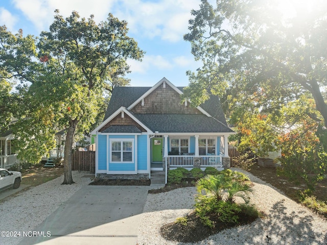 112 NE 28th St, Oak Island, NC 28465 - view of front of property with a porch, roof with shingles, and concrete driveway