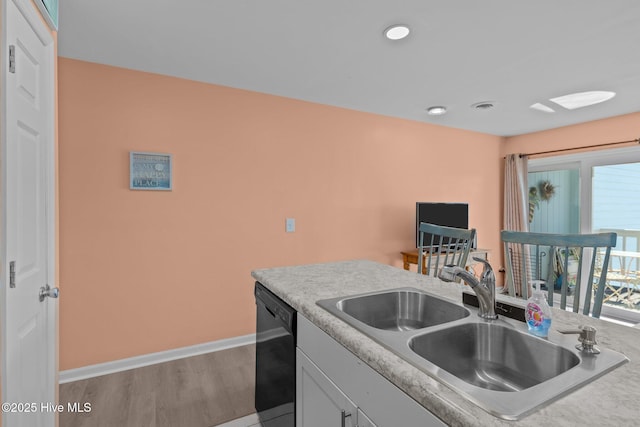 kitchen featuring light hardwood / wood-style floors, sink, black dishwasher, and plenty of natural light