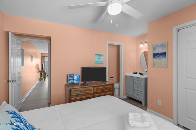 bedroom with ceiling fan, light hardwood / wood-style floors, sink, and ensuite bath