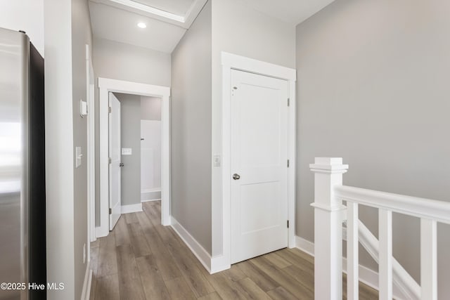 hallway with wood finished floors, an upstairs landing, and baseboards