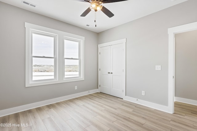 unfurnished bedroom with a ceiling fan, visible vents, baseboards, a closet, and light wood finished floors