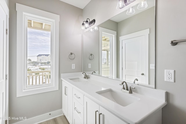 bathroom featuring double vanity, wood finished floors, a sink, and baseboards