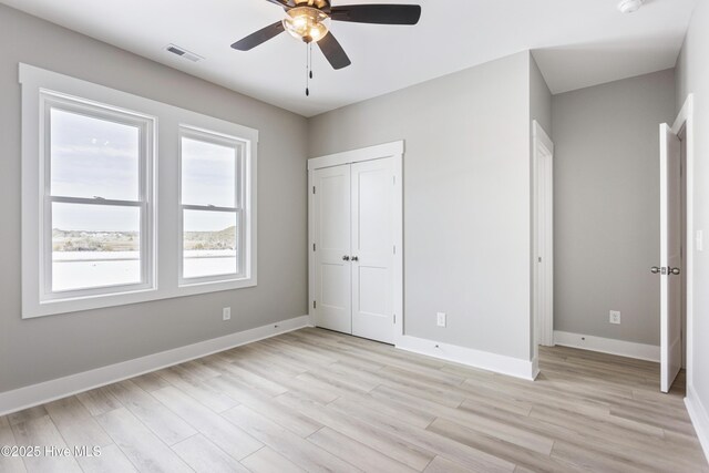 unfurnished bedroom featuring light wood-style flooring, visible vents, ceiling fan, and baseboards