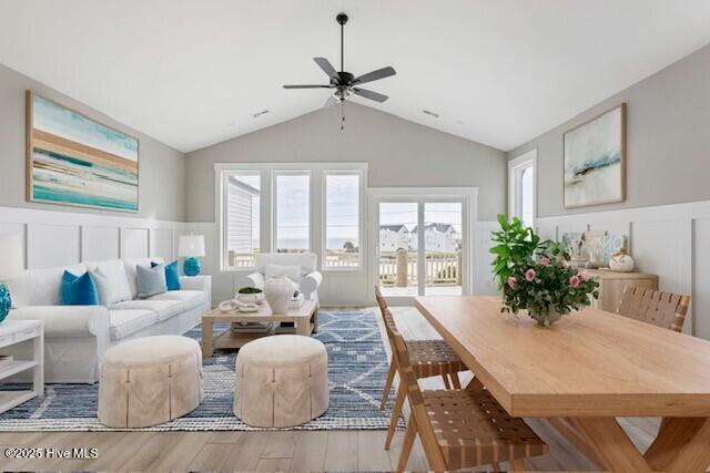 living area with a wainscoted wall, ceiling fan, wood finished floors, and lofted ceiling