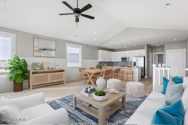 living area featuring vaulted ceiling, light wood-type flooring, wainscoting, and recessed lighting