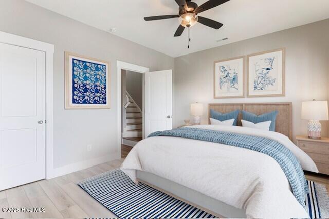 bedroom with light wood-type flooring, baseboards, and a ceiling fan