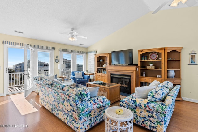 living room featuring hardwood / wood-style floors, a textured ceiling, vaulted ceiling, and ceiling fan