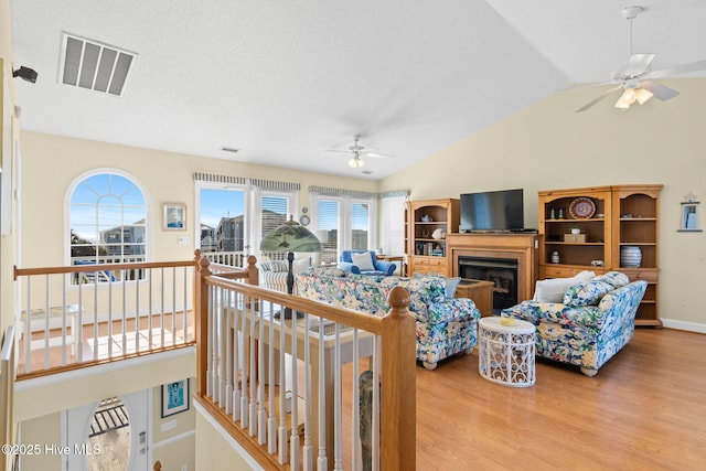 living room with a textured ceiling, ceiling fan, hardwood / wood-style floors, and lofted ceiling