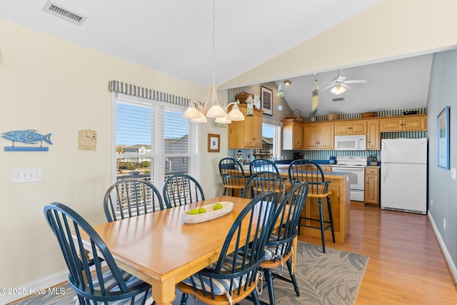 dining area with ceiling fan with notable chandelier, light wood-type flooring, and lofted ceiling