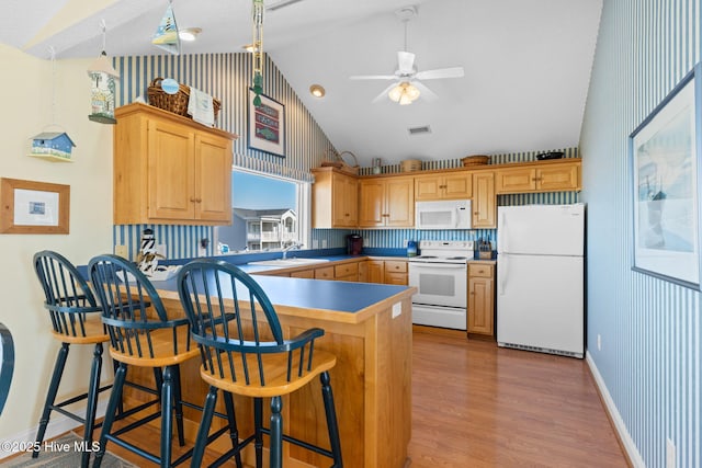 kitchen featuring a kitchen breakfast bar, white appliances, and lofted ceiling