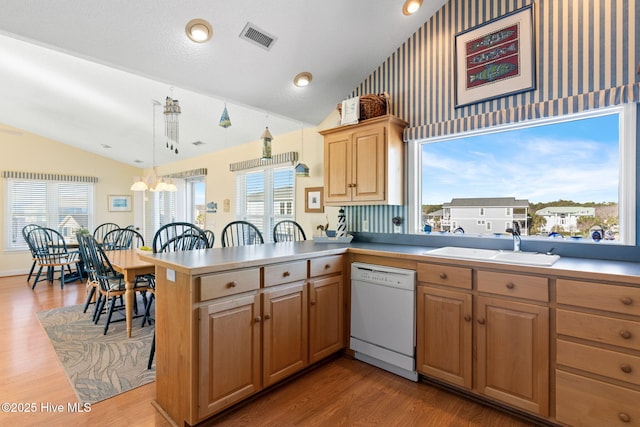 kitchen with kitchen peninsula, sink, dishwasher, hanging light fixtures, and lofted ceiling