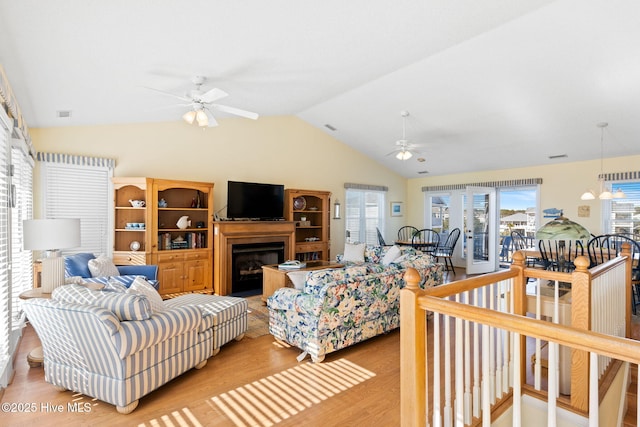 living room featuring ceiling fan, light hardwood / wood-style floors, and vaulted ceiling