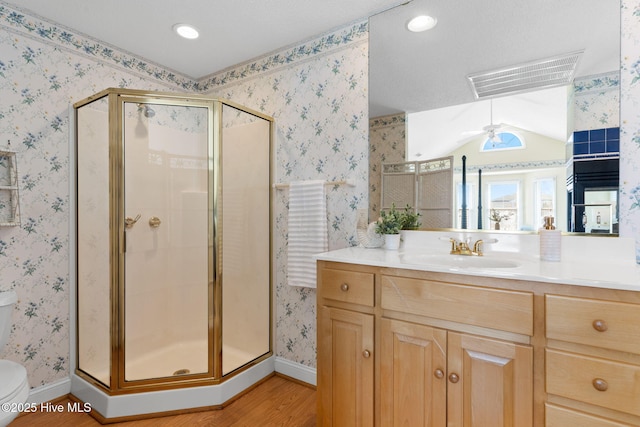 bathroom with walk in shower, vanity, ceiling fan, wood-type flooring, and toilet