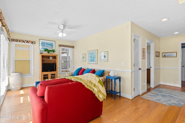 living room with ceiling fan, plenty of natural light, a textured ceiling, and hardwood / wood-style flooring