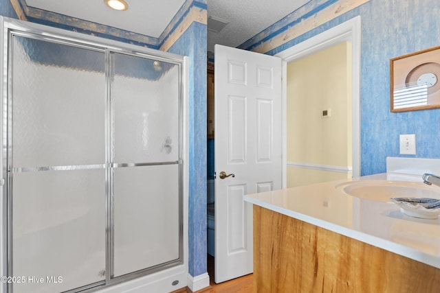 bathroom with vanity, a textured ceiling, and a shower with door