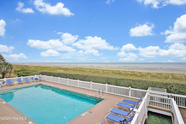 view of pool with a deck with water view and a beach view