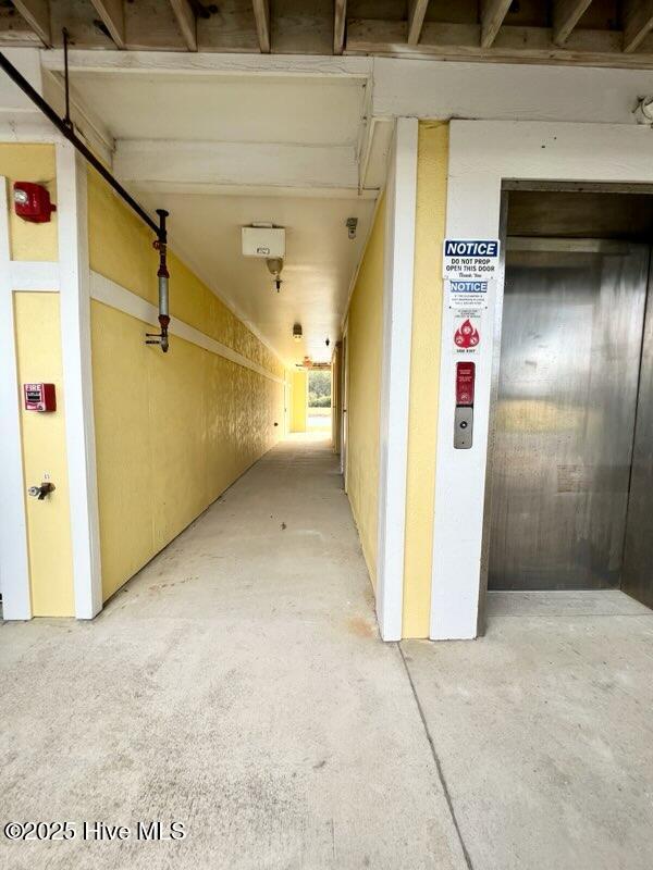 hall featuring elevator and concrete floors