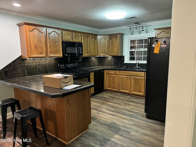 kitchen featuring kitchen peninsula, backsplash, a breakfast bar area, and black appliances