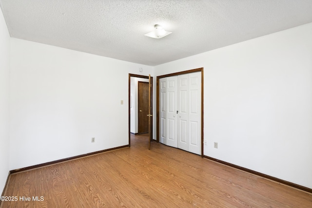 unfurnished bedroom featuring a closet, a textured ceiling, and light hardwood / wood-style flooring