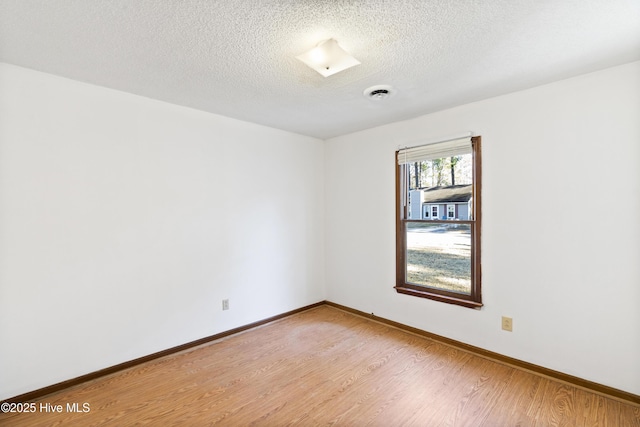 empty room featuring light wood-type flooring and a textured ceiling