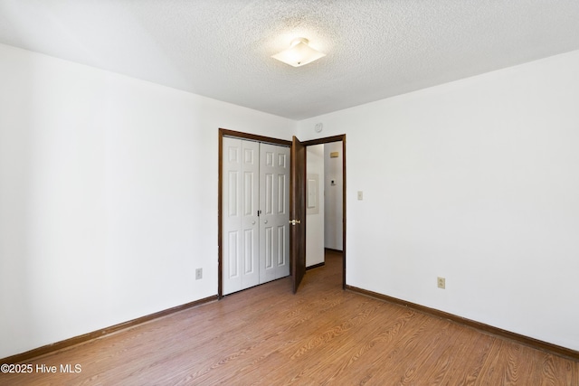 unfurnished bedroom with light wood-type flooring, a textured ceiling, and a closet