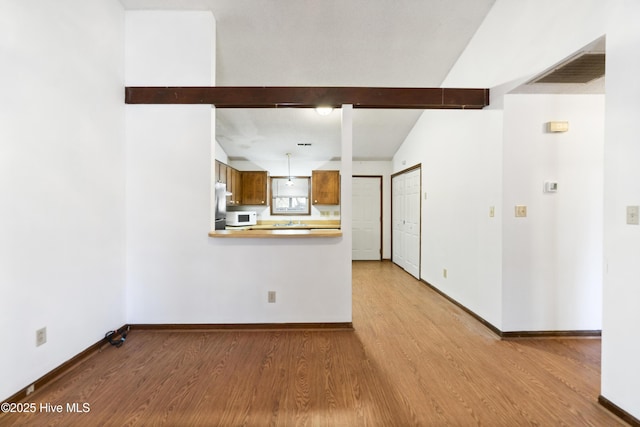 unfurnished living room with lofted ceiling with beams and light wood-type flooring