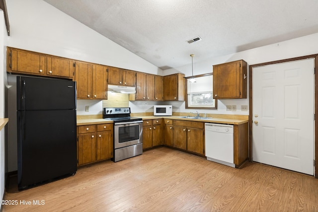 kitchen with sink, light hardwood / wood-style flooring, vaulted ceiling, a textured ceiling, and white appliances