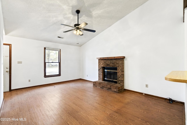 unfurnished living room featuring lofted ceiling, a brick fireplace, ceiling fan, a textured ceiling, and wood-type flooring