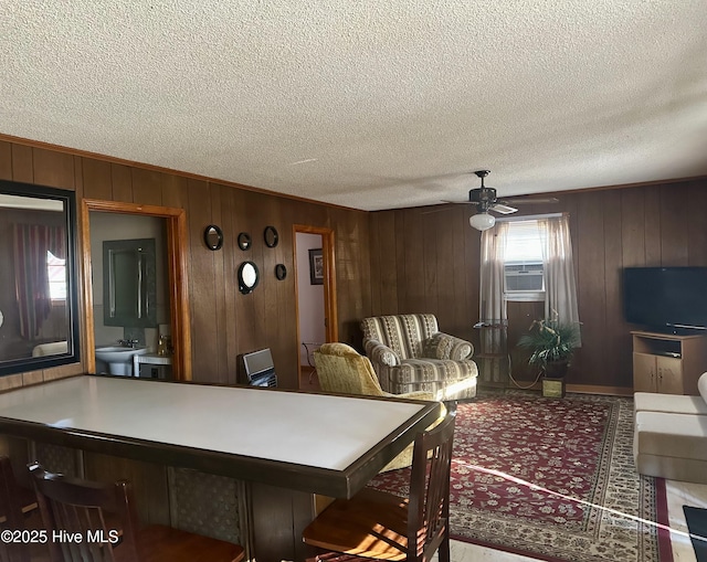 dining space with a textured ceiling, ceiling fan, wooden walls, and cooling unit