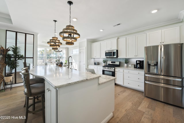 kitchen with white cabinetry, a notable chandelier, stainless steel appliances, and a center island with sink