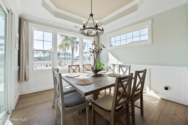 dining room featuring a raised ceiling, dark hardwood / wood-style flooring, crown molding, and a chandelier