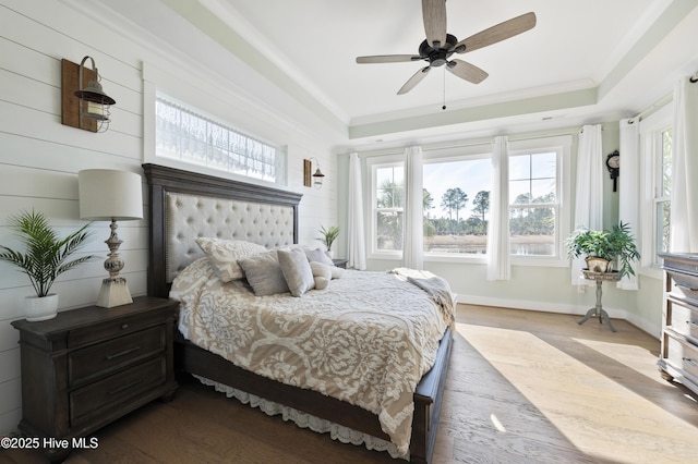 bedroom with ceiling fan, light hardwood / wood-style floors, crown molding, and a raised ceiling