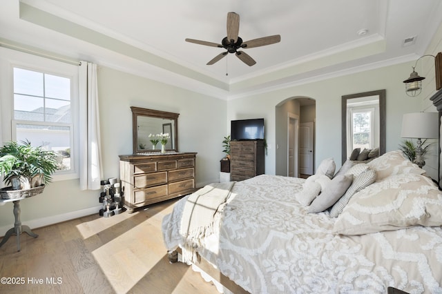 bedroom featuring a raised ceiling, ceiling fan, ornamental molding, and light hardwood / wood-style flooring