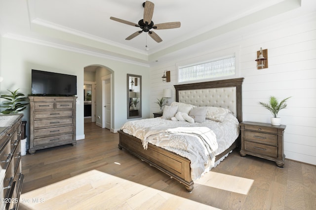 bedroom featuring dark wood-type flooring, ceiling fan, a raised ceiling, and wooden walls