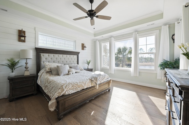 bedroom featuring light wood-type flooring, ceiling fan, crown molding, and a raised ceiling