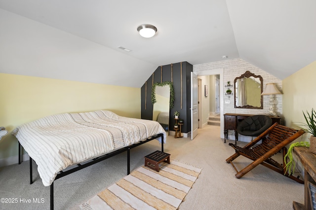 bedroom with ensuite bathroom, light carpet, and vaulted ceiling