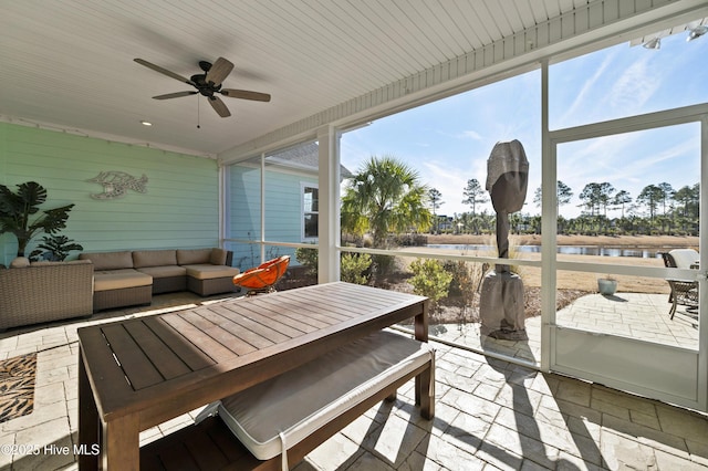 sunroom / solarium with ceiling fan and a water view