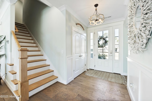 foyer entrance with dark hardwood / wood-style floors, crown molding, and a chandelier