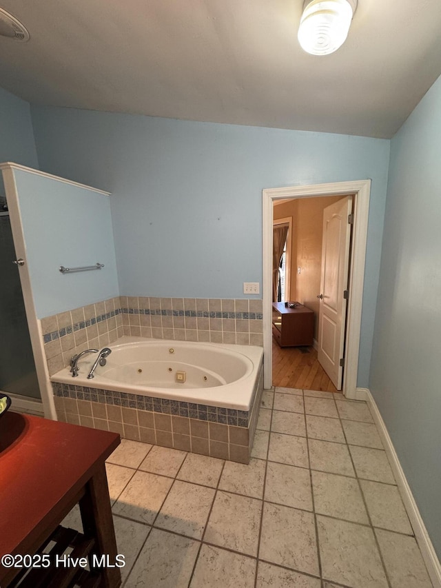 bathroom with tile patterned flooring and tiled tub