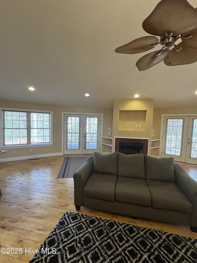 living room with ceiling fan, light hardwood / wood-style flooring, and french doors