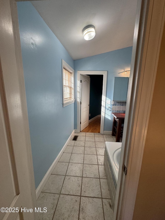 bathroom featuring tasteful backsplash, tile patterned floors, and lofted ceiling