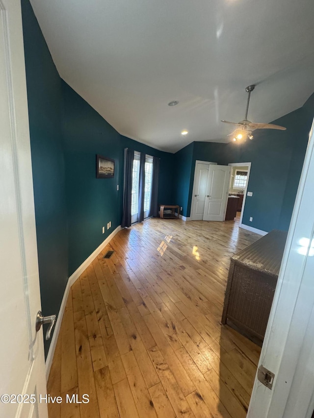 unfurnished living room featuring ceiling fan, vaulted ceiling, and light hardwood / wood-style flooring