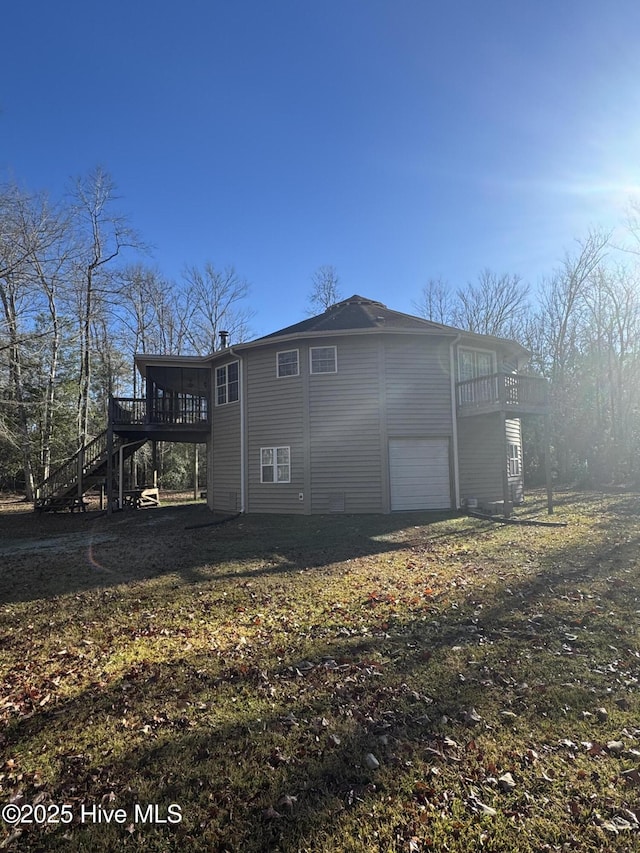 back of property featuring a deck, a garage, and a lawn