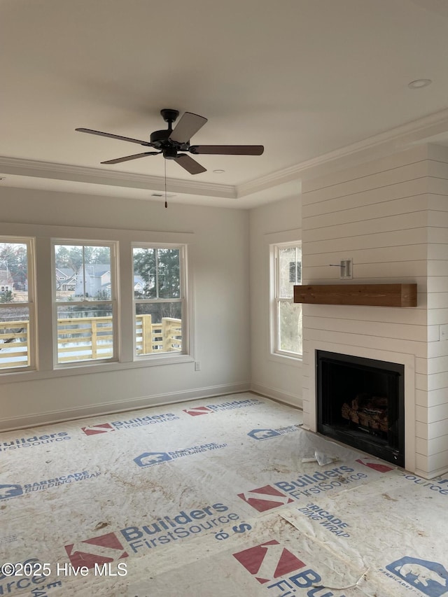 unfurnished living room with ceiling fan, a large fireplace, baseboards, and ornamental molding