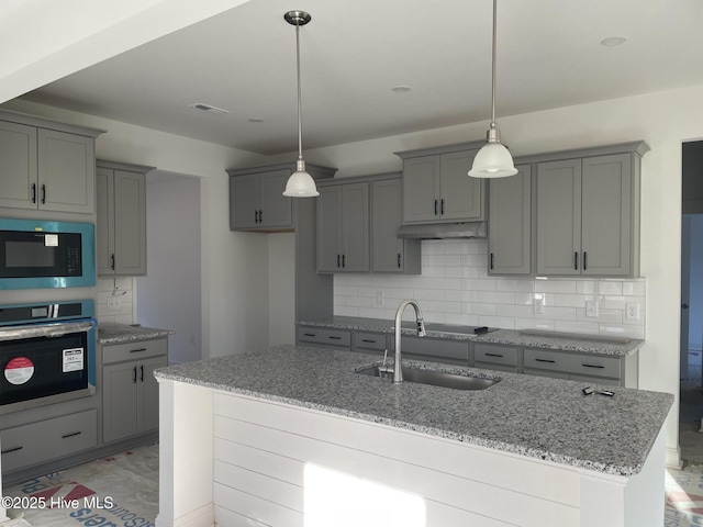 kitchen featuring built in microwave, gray cabinets, a sink, and oven